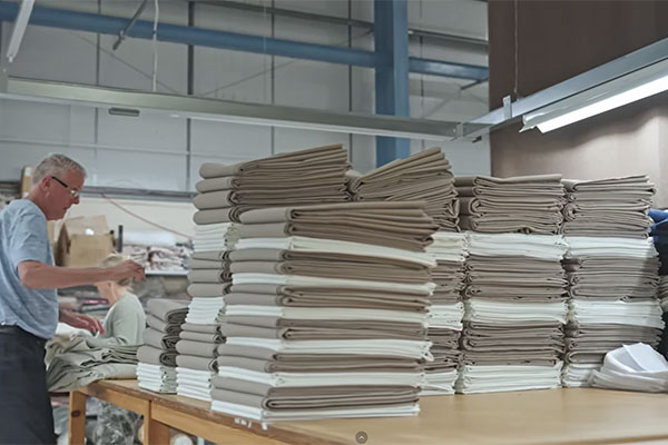 Person in the factory stood next to several piles of linen