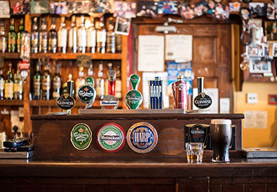 pub bar top with beer pumps in foreground and bottles in background