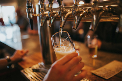 A member of staff in a pub pours a pint of beer