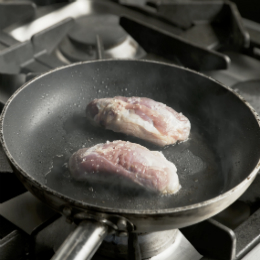 Duck breasts cooking in a pan on a stove