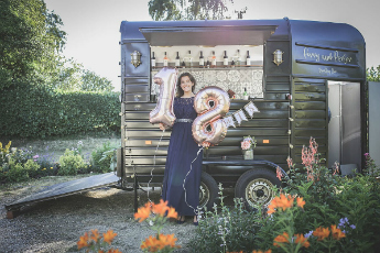 A girl with 18 balloons next to a converted horse box bar How to Convert a Horsebox article