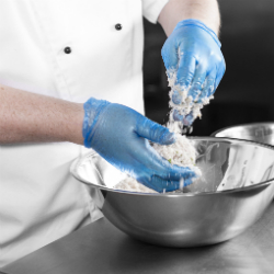 Chef Chris John wears blue gloves and coats the eggs in flour