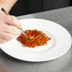 Chef Chris John uses tweezers to garnish the spaghetti which he has built into a nest
