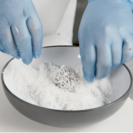 Chef Chris John wears blue vinyl gloves to cover the protein balls in desiccated coconut