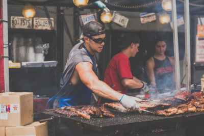 festival catering staff serving meat from a large barbecue