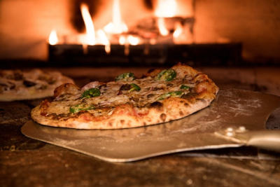 Freshly baked pizza with a pizza peel in foreground
