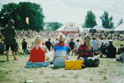 three girls sitting on grass at a festival
