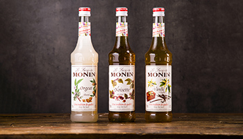 Three Bottles Of Monin Syrup Which Can Be Used To Flavour Coffees, Cocktails And Desserts