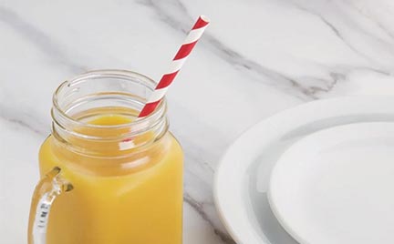 lifestyle image of orange drink and paper straw